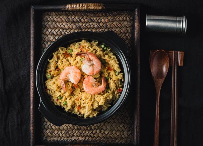 Arroz chaufa con langostinos servido en un cuenco oscuro.